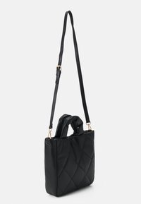 Czarna pikowana torebka z dwoma górnymi uchwytami i odpinanym paskiem na ramię. Powierzchnia jest gładka, z akcentami z metalu w złotym odcieniu.