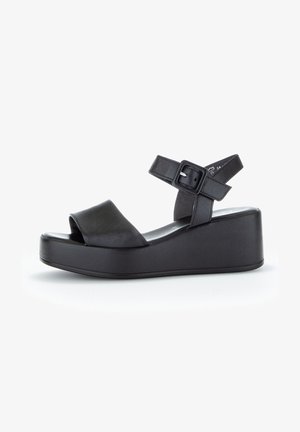 Schwarze Keilsandalen mit einem glatten Lederobermaterial, offener Zehenpartie, verstellbarem Knöchelriemen mit Schnalle und einer klobigen Plateausohle.