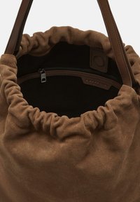 Brązowa torba tote z zamszu z marszczoną górą, skórzanymi akcentami i wewnętrzną kieszenią na zamek. Miękka tekstura i przestronny design.