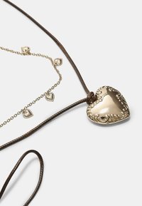 Guld hjerte vedhæng med intrikate detaljer på en brun flettet snor, med mindre guld hjerte charms fastgjort til en delikat kæde.