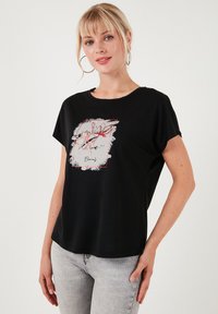 Zwarte T-shirt met korte mouwen, voorzien van een bloemenprint in het wit en rood, ronde hals en een relaxte pasvorm. Gemaakt van zacht katoen.