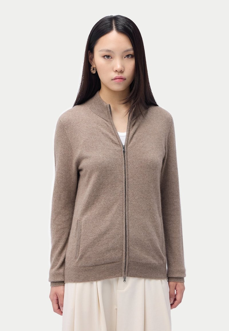 Brun zip-up cardigan tillverkad av mjukt material med rund halsringning, sidofickor och ribbade ärmslut med en jämn yta.