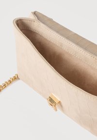 Μπεζ σουέτ τσάντα χειρός με υφή κροκόδειλου, ανοιχτό πάνω μέρος και χρυσή αλυσίδα με χρυσό ορθογώνιο κλείστρο.