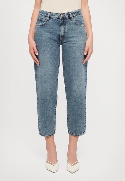 Jean en denim bleu moyen avec une taille haute, coupe droite et ourlets à revers. Caractéristiques d'un design classique à cinq poches et fermeture à bouton sur le devant.