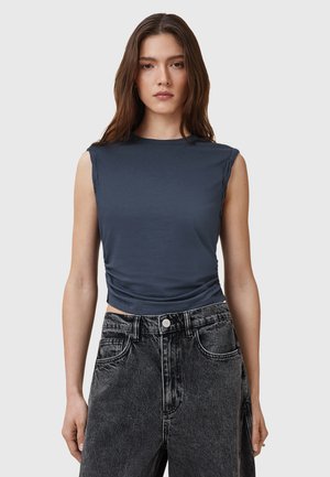 Dark blue sleeveless top with a high neckline, featuring side ruching and soft, lightweight fabric. Paired with high-waisted black denim shorts.