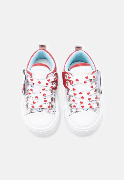 Λευκά παιδικά αθλητικά παπούτσια με κόκκινο περίγραμμα, κορδόνια με σχέδιο καρδιές και καρτούν πρόσωπα στις πλευρές, φωτογραφημένα από πάνω σε λευκό φόντο.