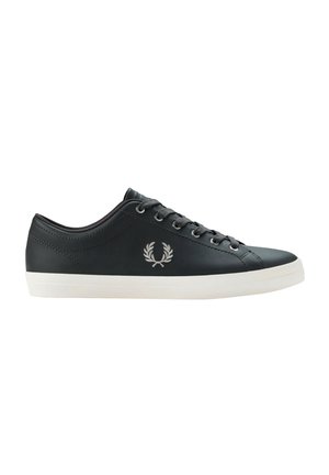 Zapatilla baja de cuero negra con cordones negros, suela blanca y logo bordado de corona de laurel en el lateral.