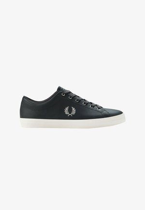 Zapatilla baja de cuero negra con cordones negros, suela blanca y logo bordado de corona de laurel en el lateral.