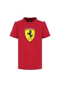 Czerwona bawełniana koszulka z krótkimi rękawami, okrągłym dekoltem i czarnym logiem skaczącego konia w żółtej tarczy z przodu. Białe akcenty na ramionach.