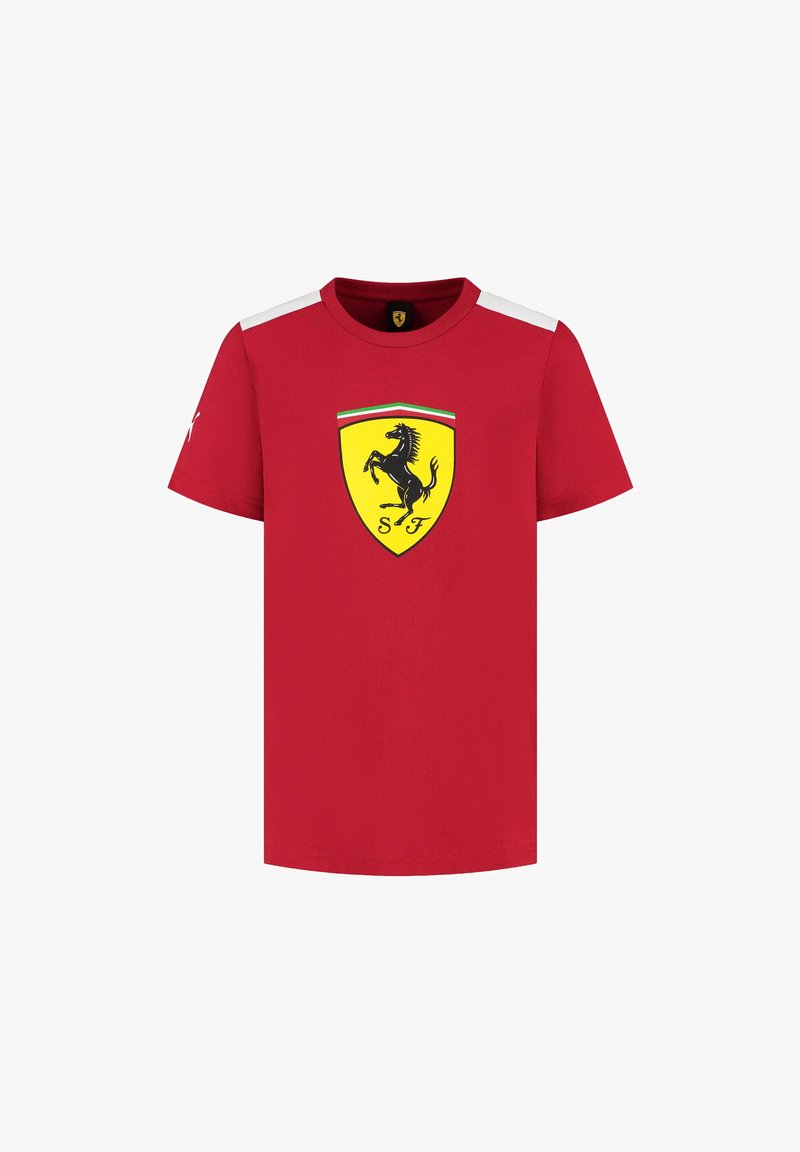 Czerwona bawełniana koszulka z krótkimi rękawami, okrągłym dekoltem i czarnym logiem skaczącego konia w żółtej tarczy z przodu. Białe akcenty na ramionach.