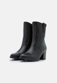 Zwarte leren enkellaarzen met een gladde afwerking, puntige neus en een blokhak. Voorzien van zijkanten met stiksel en een trekloop achterop.