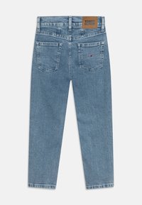 Světle modré džíny s rovnou nohavicí, s koženou štítkovou nášivkou na zadní straně a dvěma zadními kapsami se švy.