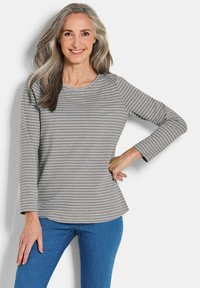 Grijze longsleeve top met witte horizontale strepen, ronde halslijn en een iets uitgeronde zoom. Gecombineerd met blauwe spijkerbroek.