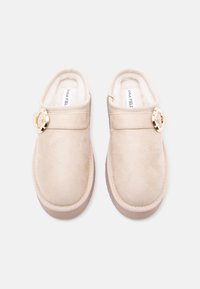 Beiga slip-on skor med en mjuk mockaliknande yta, med en dekorativ accent i guldton och en plyschfôring.