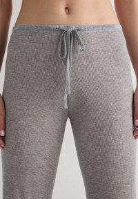 Šedé žebrované pohodlné kalhoty s uvázatelným páskem a měkkou texturou, se vzorem vodorovných pruhů po celém povrchu.
