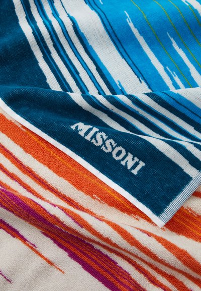 Puuvillane randarätik, millel on erksad triibud sinises, oranžis ja roosas, pehme tekstuuriga ning "MISSONI" brändinguga ääres.