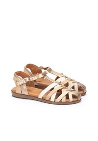 Sandali piatti strappy in oro metallico e bianco, con suola piatta, fibbia regolabile e design con punta aperta. Texture liscia con uno stile minimalista.