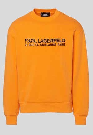 Pomarańczowa bluza z okrągłym dekoltem z czarnym napisem "KARL LAGERFELD 21 RUE ST-GUILLAUME PARIS" na środku klatki piersiowej.