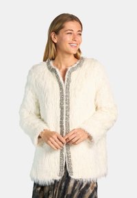 Chaqueta de pelo sintético blanco con acabado texturizado, que presenta un ribete decorado en tono plateado a lo largo del frente. Corte holgado con mangas largas.