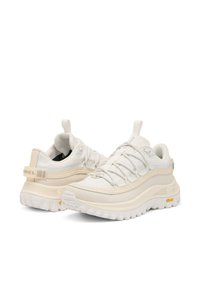 Valkoiset urheilukengät, joissa on teksturoitu verkkopäällinen, joustava nauhoitusjärjestelmä, pehmustettu kaulus ja paksu kumipohja, jossa on Vibram-logo.