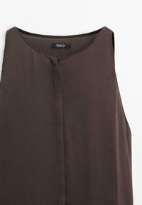 Top senza maniche color marrone scuro con una finitura testurizzata, caratterizzato da un colletto rotondo e una chiusura frontale con bottoni. Etichetta visibile all'interno.