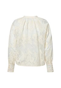 Blusa crema con ricami floreali, maniche lunghe a sbuffo, polsini con bottoni e scollo rotondo. Tessuto leggero con dettaglio testurizzato.