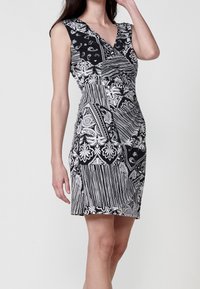 Robe noir et blanc avec un décolleté en V profond, des manches courtes, et un mélange de motifs abstraits et floraux avec des textures variées.