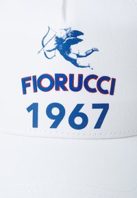 Fehér sapka, kék grafikával, amelyen egy cherub látható, és a "FIORUCCI 1967" felirat kék és piros színben. Finom textúrájú anyagból készült.