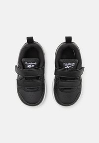 Crne tenisice s gornjim dijelom od sintetičke kože, čičak trake, perforirani detalj na prstima i bijela gumena potplat. Reebok logotip na jeziku.