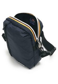 Navy fabric square bag with contrasting zipper, adjustable strap, and a small side buckle. Minimalist design with padded texture.