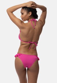 Rožinė bikini maudymosi kostiumėlis su kaklo užrišimu ir suvarstomu nugaros uždengimu. Apačioje yra raukiniai šoniniuose kraštuose. Sklandus paviršius, abi dalys suderintos.