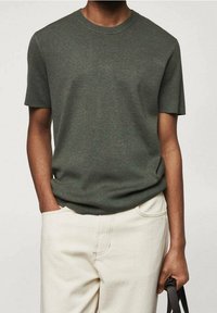 Kakhi kortærmet crewneck t-shirt i strikstof med en afslappet silhuet. Bæres med off-white bukser, hænderne i lommen.