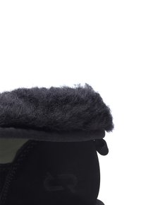 Botas negras con un puño de piel sintética en la parte superior, con una textura suave y forma redonda, con un logo sutil en el costado.