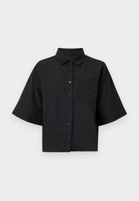 Camiseta preta cropped com colarinho, mangas curtas, fecho por botão e detalhe de textura em ondas subtil. Apresenta um único bolso no peito.