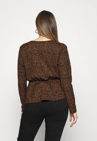 Blusa a maniche lunghe nera e arancione con un motivo, dotata di un nastro in vita, caratterizzata da una vestibilità rilassata e un tessuto testurizzato per un interesse visivo aggiuntivo.