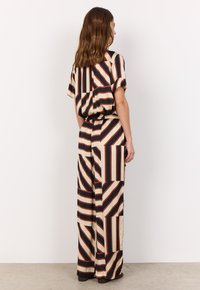 Striped wide-leg outfit in beige, black, and rust. Features a loose fit with short sleeves and an elastic waist; includes contrasting patterns.