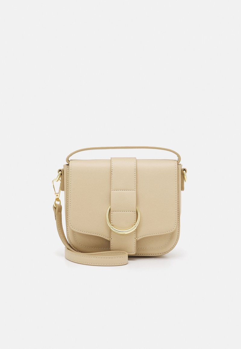Beige læder crossbody taske med en rund metalaccent, justerbar rem, klaplukning og minimalistisk design. Glat tekstur med syning detaljer.
