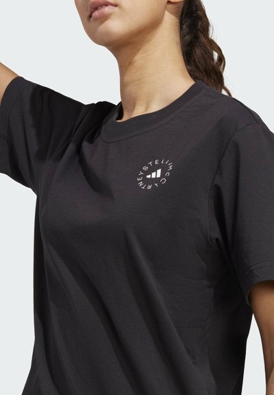Musthave musta puuvillane T-särk lühikeste varrukatega, ümmargune kaelus ja vasakul rinnal ringikujuline valge logo, mis sisaldab julgeid graafilisi elemente.