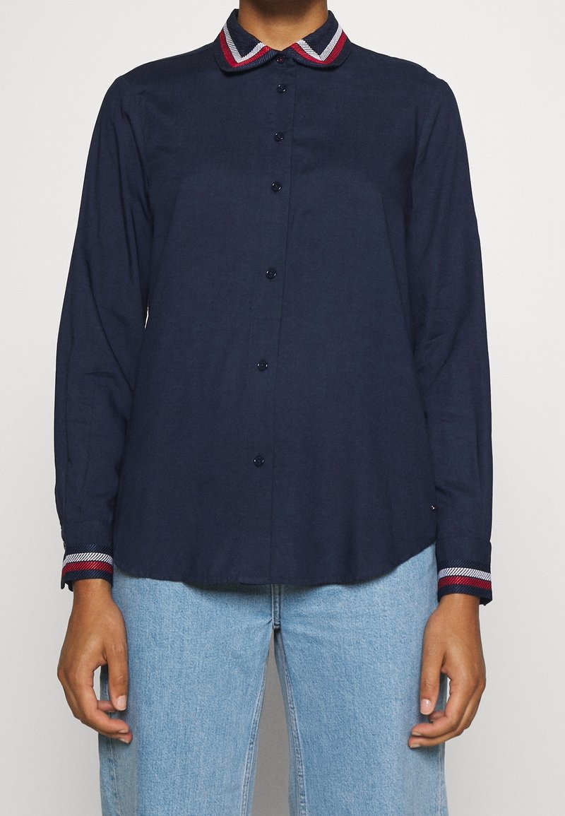 Marinblå långärmad skjorta med knappstängning fram, kontrasterande krage och manschetter med röd, vit och blå rand, klassisk passform.
