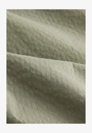Tekstilstof i dæmpet olivengrøn, der har et tekstureret væv med synlige fibre og subtile mønstre, hvilket skaber en blød og fleksibel overflade.