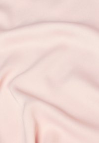 Mjuk ljusrosa tyg med mjuka veck och en slät textur som skapar subtila skuggor och högdagrar.