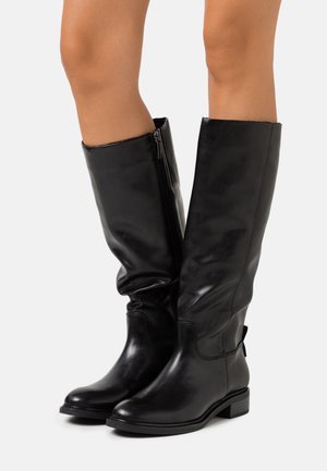 Botas de cuero negro hasta la rodilla con una textura suave, punta redondeada, cremallera lateral y tacón bajo en bloque. Diseño holgado para un ajuste flexible.