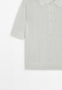 Biała koszulka polo z krótkim rękawem, o fakturowanym, perforowanym wzorze dzianiny i guzikami przy kołnierzyku, prezentowana na białym tle.