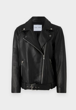 Svart läderbikerjacka med silverfärgade dragkedjor, bälte i midjan och spetsiga slag. Har två fickor med dragkedja och en slät yta.