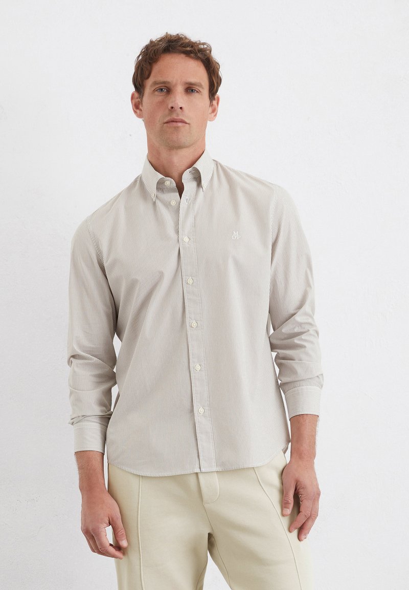 Helle beige Button-up-Hemd mit dünnen vertikalen Streifen, langen Ärmeln und einem kleinen, auf der Brust gestickten Logo. Weicher Baumwollstoff.