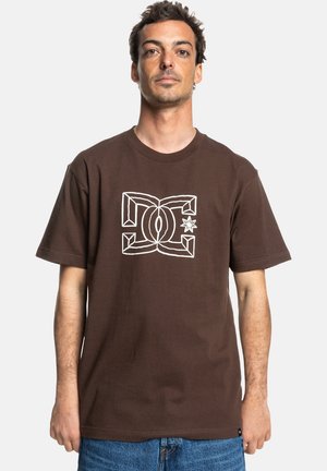 Brown cotton t-shirt with short sleeves. Features a white graphic logo design in the center. Classic fit and soft texture.