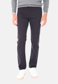 Chinos in cotone blu navy con vestibilità dritta, dotati di cinque tasche e una texture liscia, abbinati a sneakers bianche.