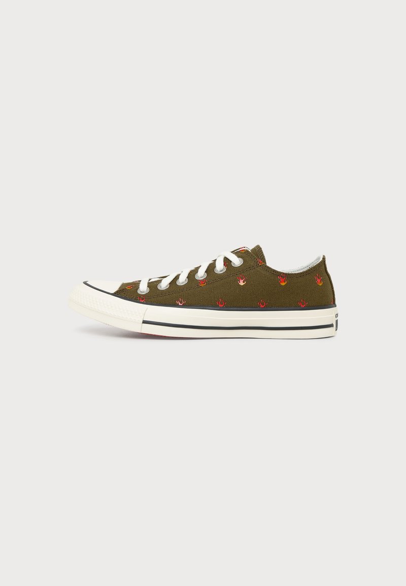 Χαμηλού τύπου ελιάς πράσινο πάνινο αθλητικό παπούτσι με λευκά κορδόνια και μικρά κόκκινα μοτίβα φλόγας, λευκή καουτσούκ σόλα και μαύρες ρίγες.
