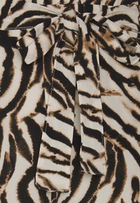Printed fabric featuring a beige background with black and brown tiger stripes. Includes a tied bow detail made from the same material.