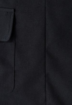 Schwarzer Stoff mit einer strukturierten Oberfläche; verfügt über eine kleine Pattentasche und sichtbare Nähte. Die Oberfläche ist glatt mit einem dezenten Glanz.